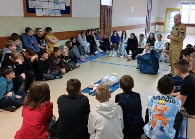Uczniowie na korytarzu szkolnym słuchają prelekcji.