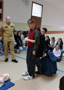 Uczniowie ćwiczą sposób udzielania pomocy w przypadku zakrztuszenia się.
