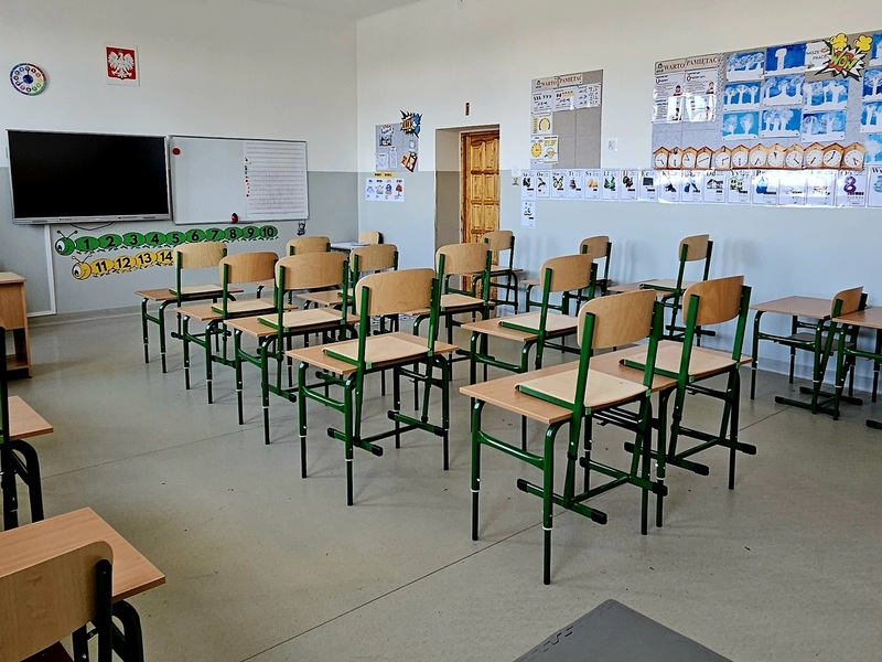 klasa lekcyjna,  w rzędzie ustawione ławki, na ścianach tablice