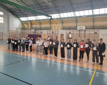 Uczniowie  uhonorowani dyplomami gratulacyjnymi za osiągnięcia edukacyjne i sportowe na hali sportowej  z panią dyrektor przed społecznością szkolną.