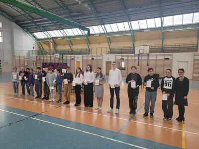 Uczniowie  uhonorowani dyplomami gratulacyjnymi za osiągnięcia edukacyjne i sportowe na hali sportowej  z panią dyrektor przed społecznością szkolną.