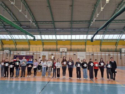 Uczniowie  uhonorowani dyplomami gratulacyjnymi za osiągnięcia edukacyjne i sportowe na hali sportowej  z panią dyrektor przed społecznością szkolną.