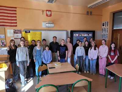Uczniowie w klasie lekcyjnej w towarzystwie nauczyciela oraz przedstawiciela projektu