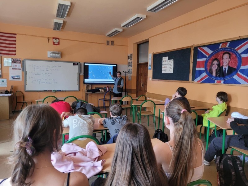 Uczniowie w sali lekcyjnej słuchający prelekcji i oglądający film.