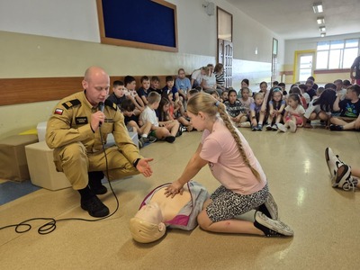 Pokaz masażu serca prowadzony przez ucznia na fantomie  pod okiem strażaka.