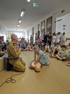 Pokaz masażu serca prowadzony przez ucznia na fantomie  pod okiem strażaka.