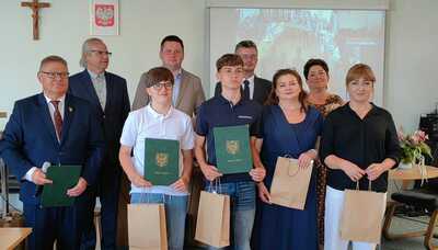 Uczniowie prezentujący dyplomy  w towarzystwie nauczycieli oraz z Burmistrzem Miasta Tuszyn i innych przedstawicieli władz.