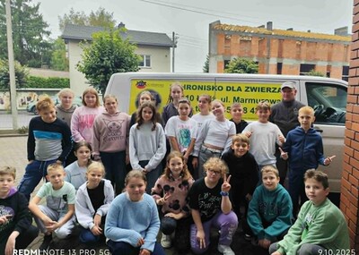 Uczniowie wraz pracownikiem schroniska przed budynkiem szkoły