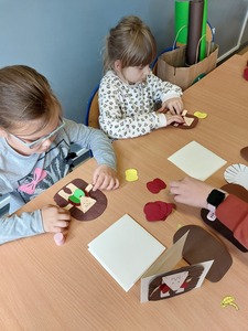 Uczniowie w świetlicy szkolnej przy stolikach wykonujący kartki dla nauczycieli.