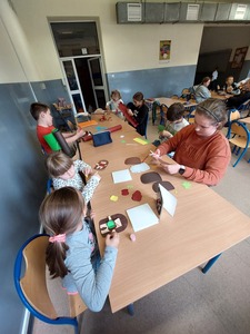 Uczniowie w świetlicy szkolnej przy stolikach wykonujący kartki dla nauczycieli.