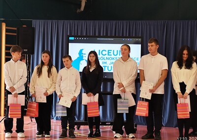 Uczniowie nagrodzeni stojący przed zgromadzonymi ludźmi