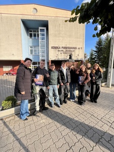 Uczniowie wraz z opiekunem przed budynkiem szkoły.