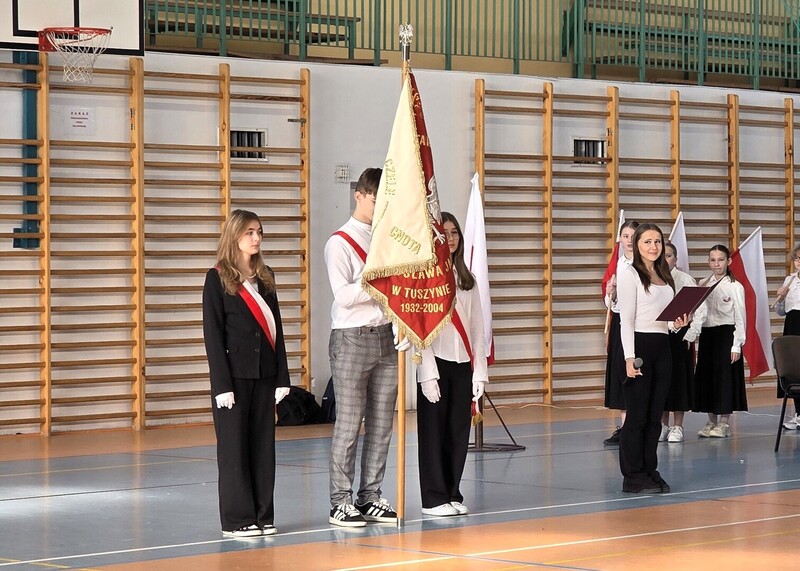 Poczet sztandarowy szkoły otwierający uroczysty apel z okazji Święta Niepodległości na hali sportowej .