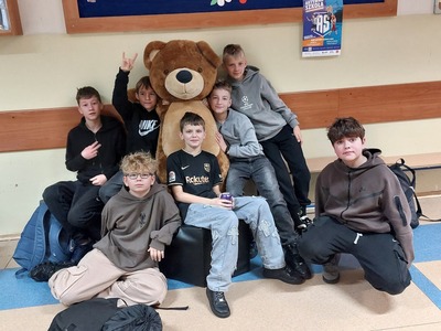 Zdjęcie grupowe uczniów na korytarzu szkolnym z pluszowymi misiami.