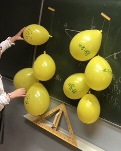 Żółte balony z działaniami na tle zielonej tablicy.
