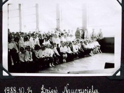 Uczniowie zgromadzeni na sali gimnastycznej. W pierwszym rzędzie siedzą dzieci, za nim stoją pozostali uczniowie.