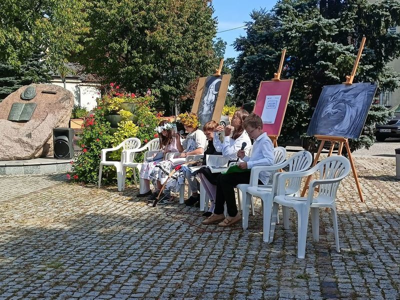 Plac Reymonta w Tuszynie. Pięcioro uczniów siedzi na krzesłach i czytają fragmenty Ballad i romansów Mickiewicza.