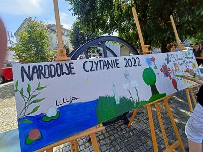 Rozpięty na sztalugach długi plakat pod hasłem "NARODOWE CZYTANIE 2022". 