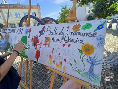 Rozpięty na sztalugach długi plakat pod hasłem "NARODOWE CZYTANIE 2022. Ballady i romanse. Adam Mickiewicz".