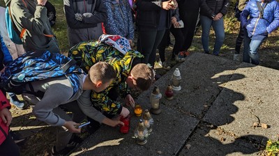 Uczniowie klas piątych zapalają znicze na mogile nieznanych żołnierzy znajdującej się na terenie Rezerwatu Przyrody MOLENDA.