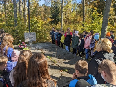 Uczniowie klas piątych wraz z opiekunami zgromadzeni przy leśnej mogile nieznanego żołnierza.