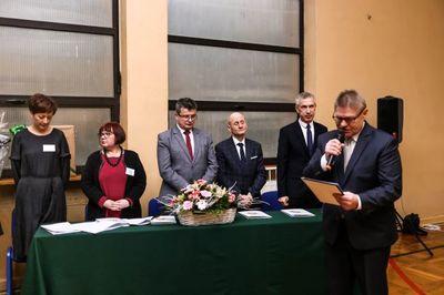 Stół prezydialny. Przy nim Dyrekcja Szkoły, przedstawiciele władz miasta Tuszyna. Przemawia radny dzielnicy Tuszyn - Las.