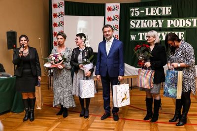Sala gimnastyczna. Na środku sceny dyrektorzy szkół i przedszkoli z Tuszyna i okolic. W rękach trzymają kwiaty i upominki.
