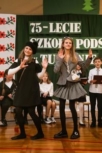 Scena na sali gimnastycznej. W centralnej części uczennice prezentujące modę z lat dziewięćdziesiątych.