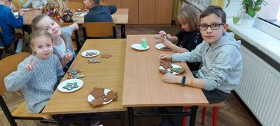 Stół, przy którym siedzi czworo dzieci dekorujących pierniki.