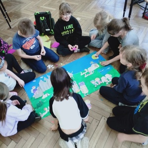 Grupa dzieci przygotowująca plakat dotyczący planów na weekend majowy.