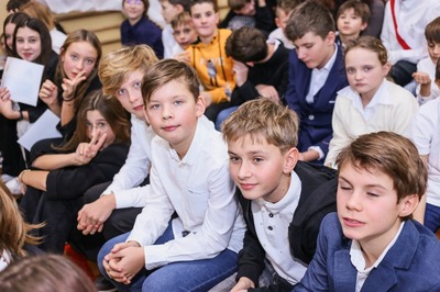 Wnętrze sali gimnastycznej. Na ławkach uczniowie w strojach galowych.