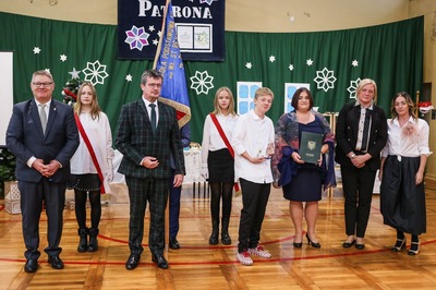 Na środku sali gimnastycznej grupa 9 osób, w tym Burmistrz Miasta Tuszyna. W tle poczet sztandarowy.