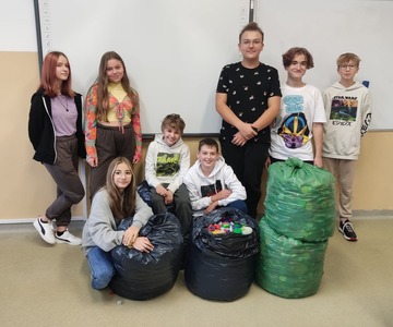 Uczniowie z workami wypełnionymi plastikowymi nakrętkami
