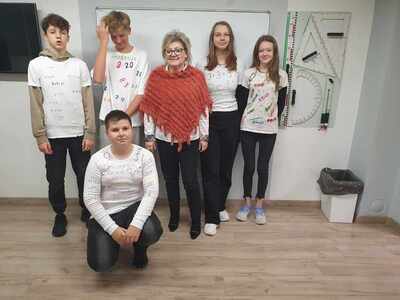 Pani dyrektor - matematyk stoi z otoczeniu uczniów w koszulkach konkursowych.