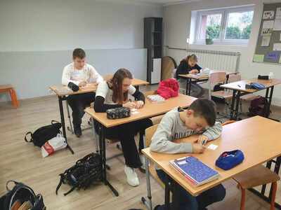 uczniowie w ławkach piszą kartkówkę