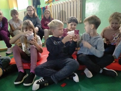 Grupa dzieci siedzi na podłodze i przyglądają się zwierzętom.