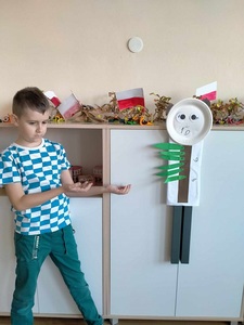 Chłopiec obok swojej pracy plastycznej