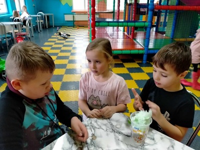 Jedna dziewczynka i dwóch chłopców siedzi przy stoliku.