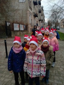 Uczniowie klas 0-III w czapkach Mikołaja, stoją parami