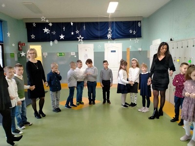 Dzieci z nauczycielkami stoją w kole i składają sobie życzenia.