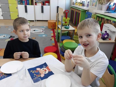 Chłopcy przy stole trzymają opłatek.