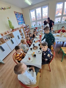 Dzieci siedzą przy wigilijnym stole.