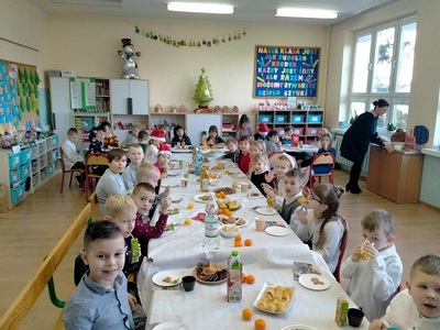 Dzieci z klasy I i II siedzą przy wigilijnym stole.
