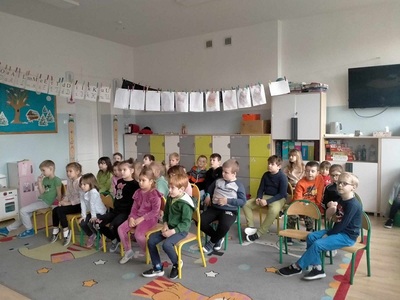 Dzieci siedzą na krzesełkach.
