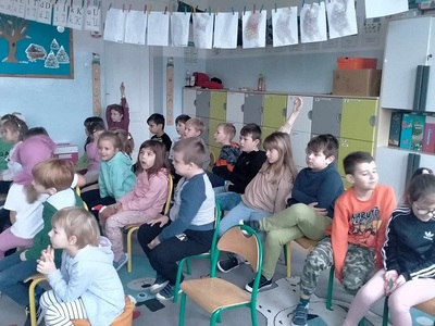 Dzieci siedzą na krzesełkach.
