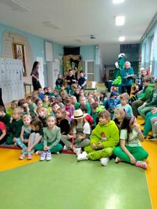Dzieci z klas 0-3 siedzą na podłodze na korytarzu szkolnym