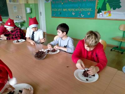 Uczniowie z klasy trzeciej siedzą przy stole i wykonują szyszkę