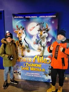 Dwóch chłopców stoi przy plakacie filmu.
