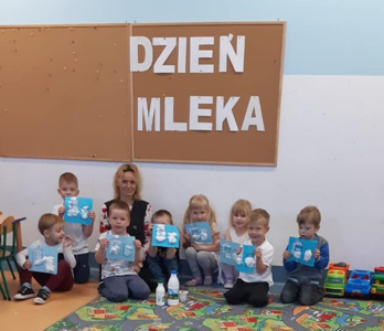 Napis dzień mleka, dzieci siedzą z nauczycielem