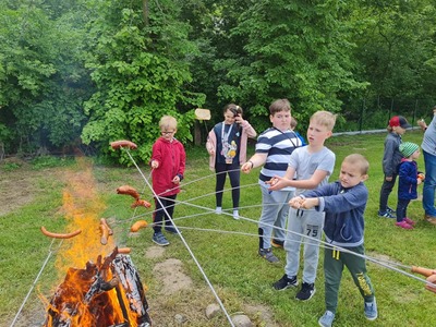 dzieci pieką kiełbaski nad ogniskiem